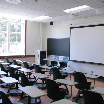 View of front of room with projection screen, lectern and tables