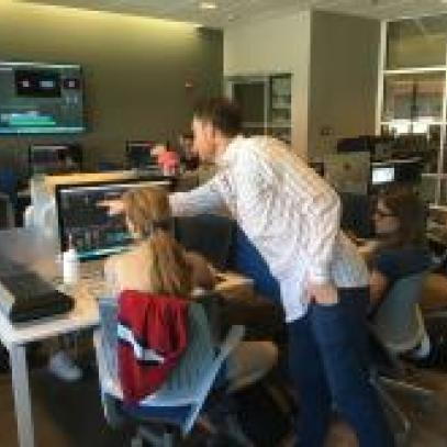 Image of faculty pointing to screen in a media lab