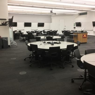 Large room with round tables and seating, TVs on walls throughout